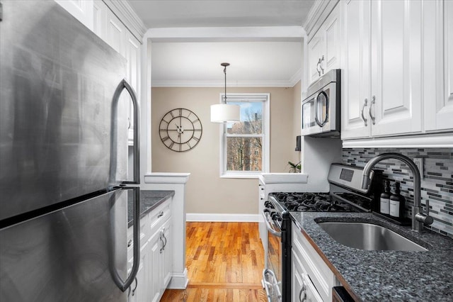 kitchen featuring tasteful backsplash, white cabinetry, dark stone countertops, stainless steel appliances, and crown molding