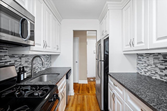 kitchen with white cabinets, light wood finished floors, dark stone counters, and stainless steel appliances