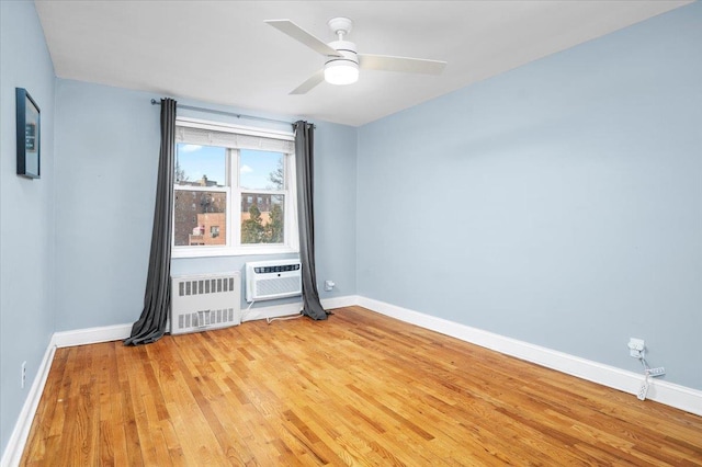 empty room featuring ceiling fan, baseboards, light wood-style floors, an AC wall unit, and radiator