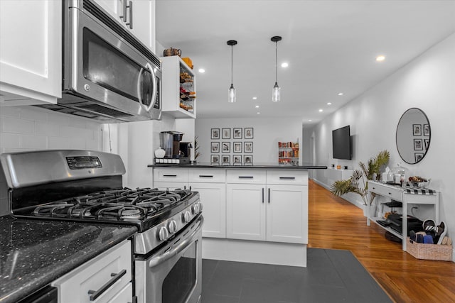 kitchen featuring dark wood-type flooring, white cabinetry, hanging light fixtures, stainless steel appliances, and backsplash