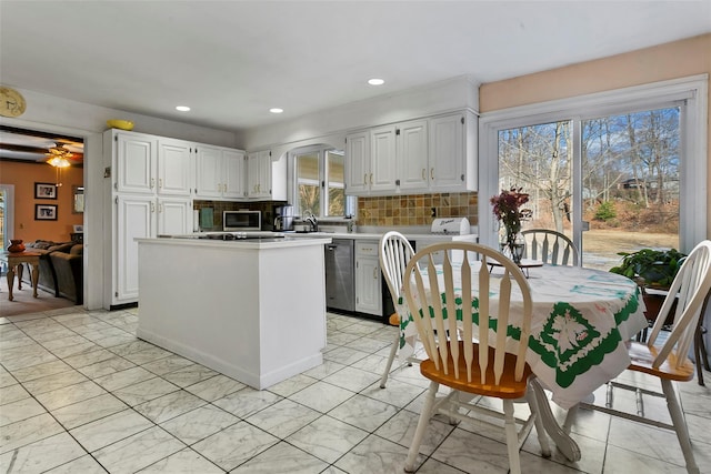 kitchen featuring stainless steel appliances, light countertops, decorative backsplash, white cabinets, and a kitchen island