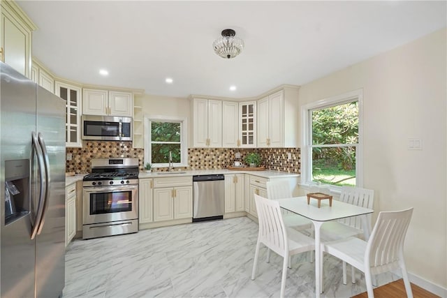 kitchen featuring cream cabinets, stainless steel appliances, light countertops, and a sink