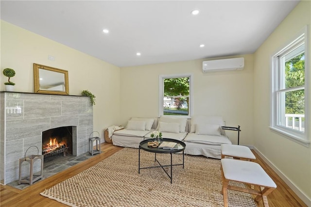 living area with baseboards, recessed lighting, a fireplace, wood finished floors, and a wall mounted AC