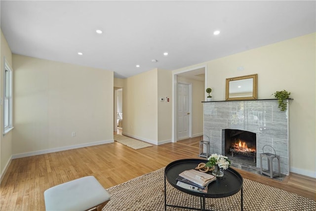 living area featuring recessed lighting, baseboards, light wood-style flooring, and a fireplace