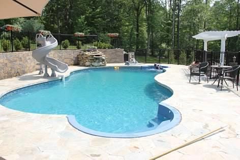 view of swimming pool featuring fence, a water slide, a fenced in pool, and a patio