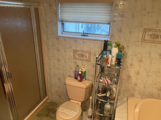 bathroom featuring tile walls, a shower with door, and toilet