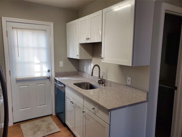 kitchen featuring sink, white cabinetry, light stone counters, dishwasher, and light hardwood / wood-style floors