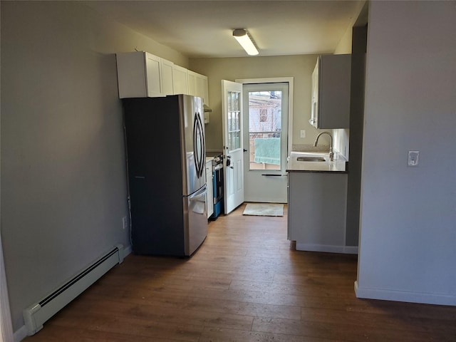 kitchen with appliances with stainless steel finishes, white cabinetry, sink, dark hardwood / wood-style flooring, and a baseboard heating unit