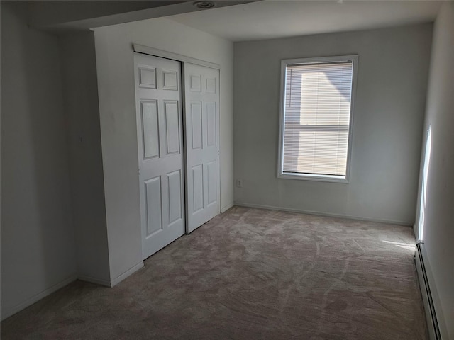 unfurnished bedroom featuring baseboard heating, carpet flooring, and a closet