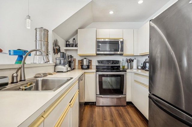 kitchen featuring sink, vaulted ceiling, hanging light fixtures, stainless steel appliances, and white cabinets