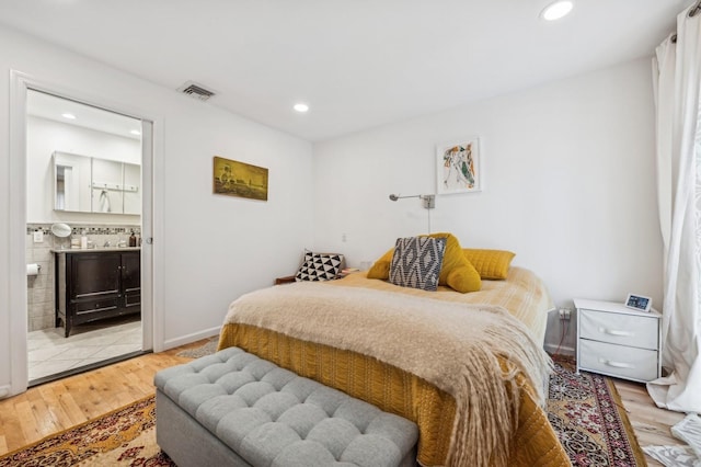 bedroom with connected bathroom and light hardwood / wood-style floors