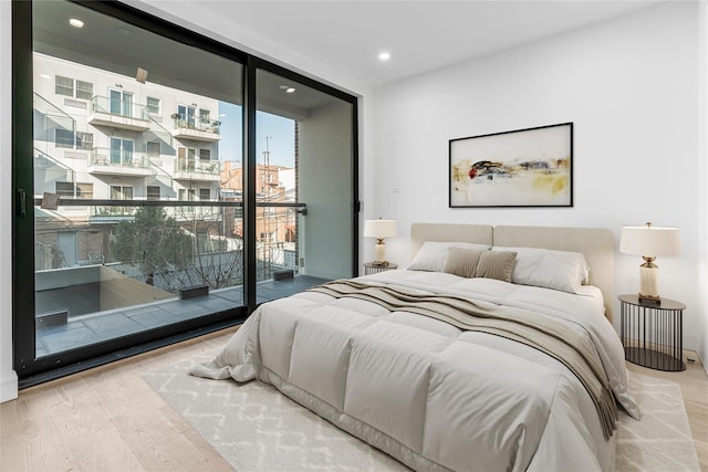 bedroom with a wall of windows, access to exterior, and hardwood / wood-style floors