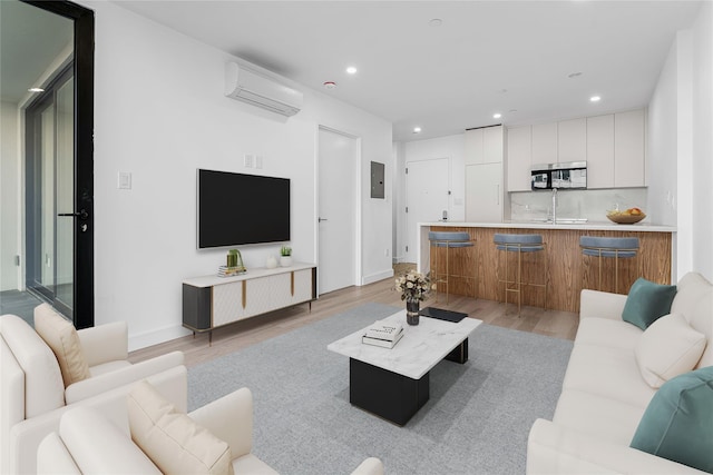 living room featuring sink, light hardwood / wood-style floors, a wall mounted AC, and electric panel