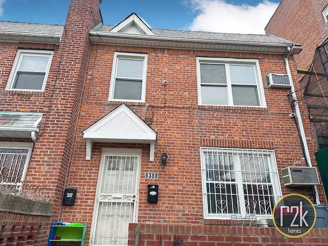 townhome / multi-family property with brick siding, a wall unit AC, and central AC