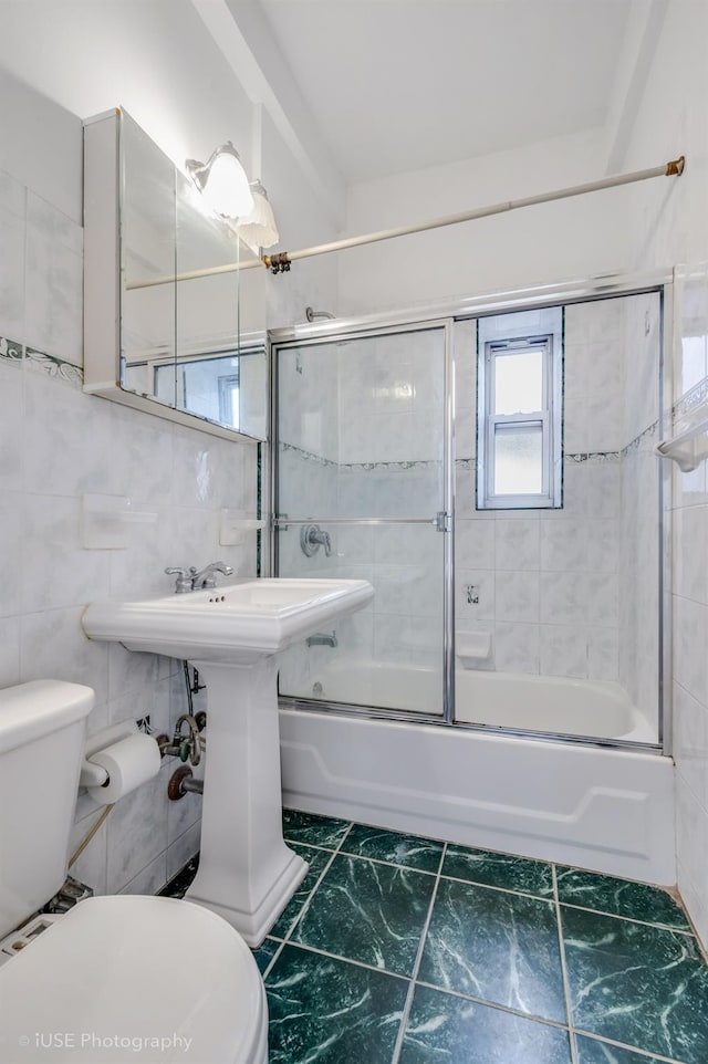 bathroom featuring enclosed tub / shower combo, tile walls, and toilet