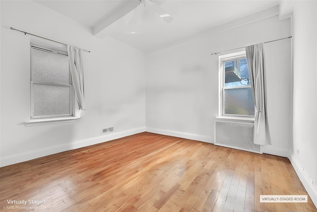 spare room featuring beamed ceiling, radiator, and hardwood / wood-style floors