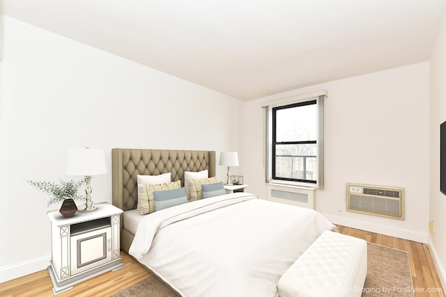 bedroom with hardwood / wood-style flooring, radiator heating unit, and a wall unit AC