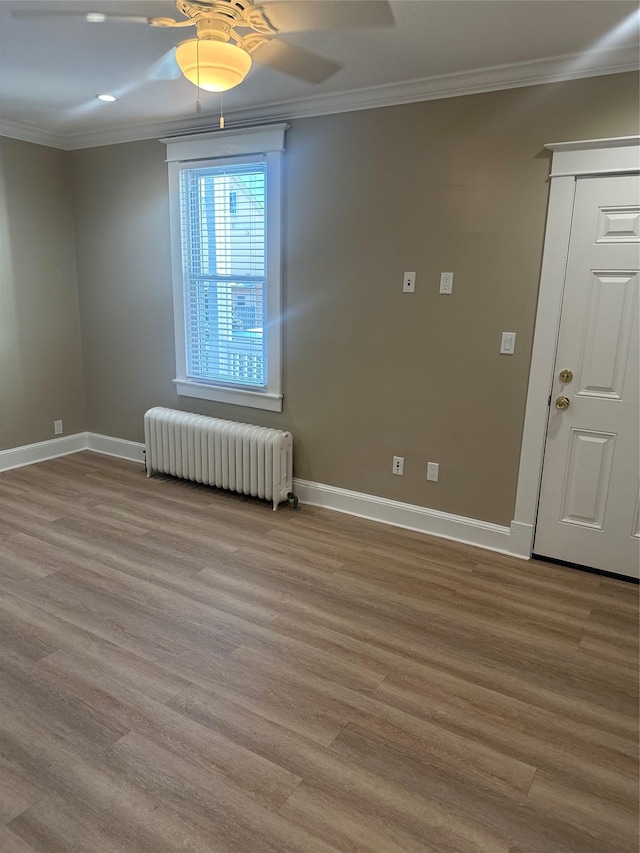 empty room with crown molding, radiator, ceiling fan, and light hardwood / wood-style flooring