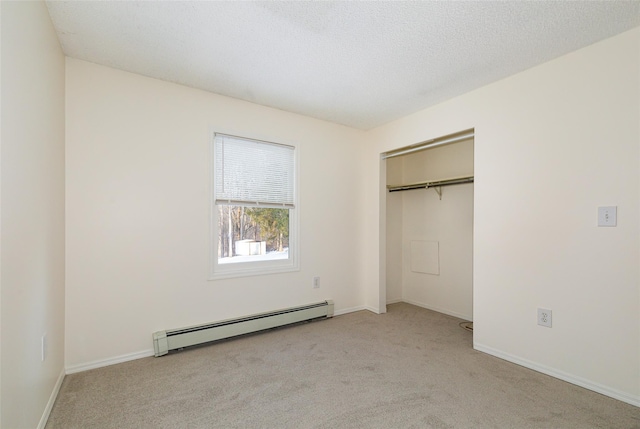 unfurnished bedroom featuring a baseboard heating unit, light colored carpet, a textured ceiling, and a closet