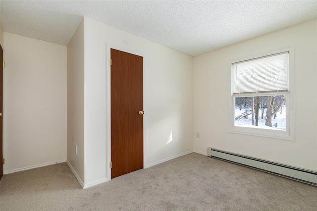 spare room with light carpet, a textured ceiling, and baseboard heating