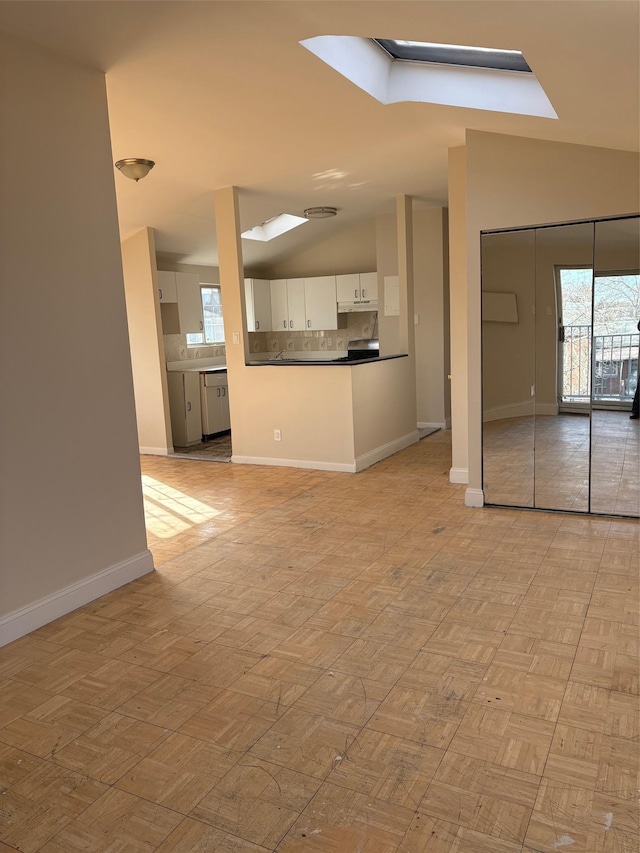 unfurnished living room with vaulted ceiling with skylight