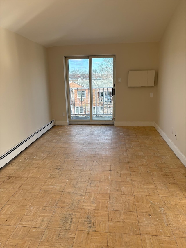 spare room featuring a baseboard heating unit and light parquet flooring