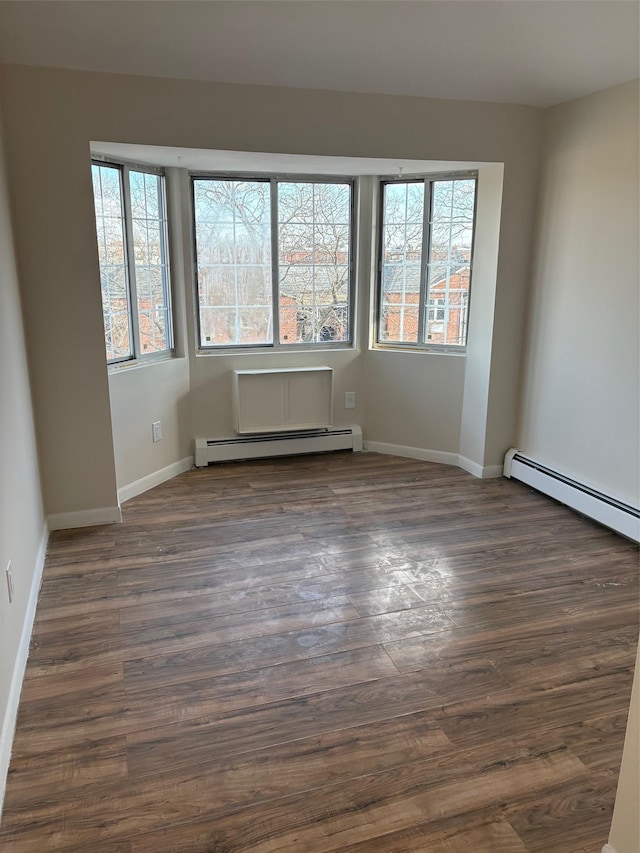 spare room featuring a baseboard radiator and dark hardwood / wood-style floors