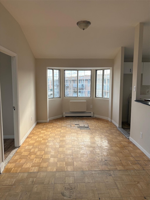 empty room featuring vaulted ceiling, a wealth of natural light, light parquet flooring, and baseboard heating