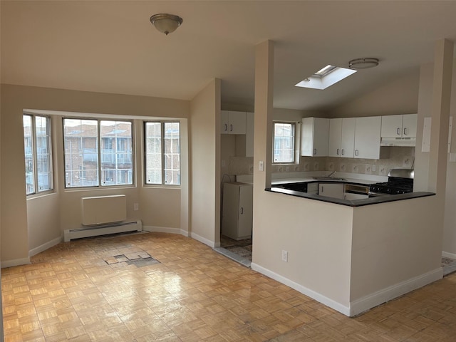 kitchen with lofted ceiling with skylight, washer and dryer, white cabinets, a baseboard heating unit, and gas range