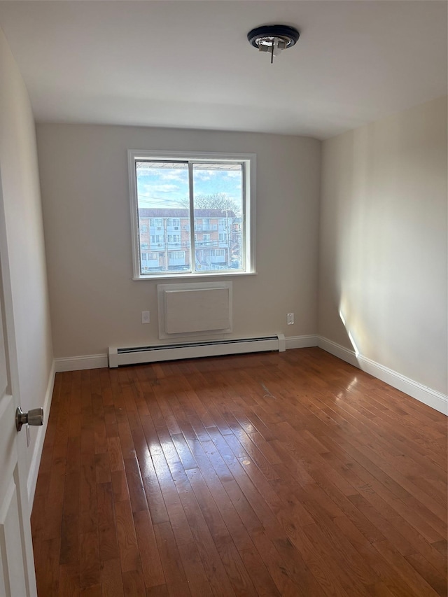 spare room with a baseboard radiator and dark hardwood / wood-style floors