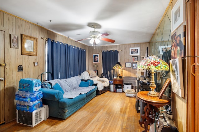 living room with hardwood / wood-style flooring, ceiling fan, and wood walls