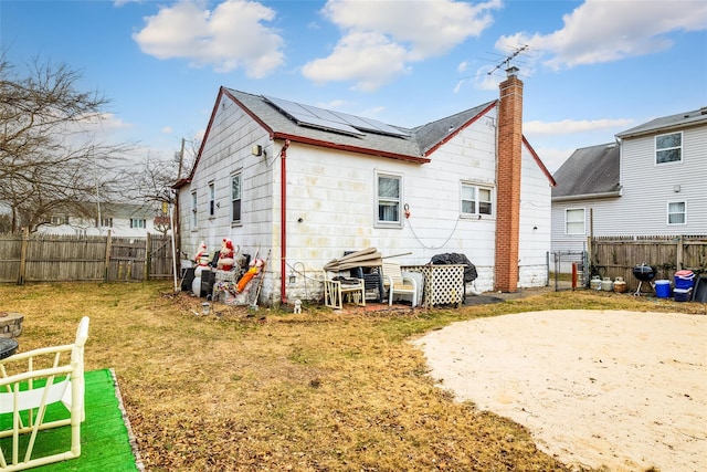 back of property featuring a lawn and solar panels