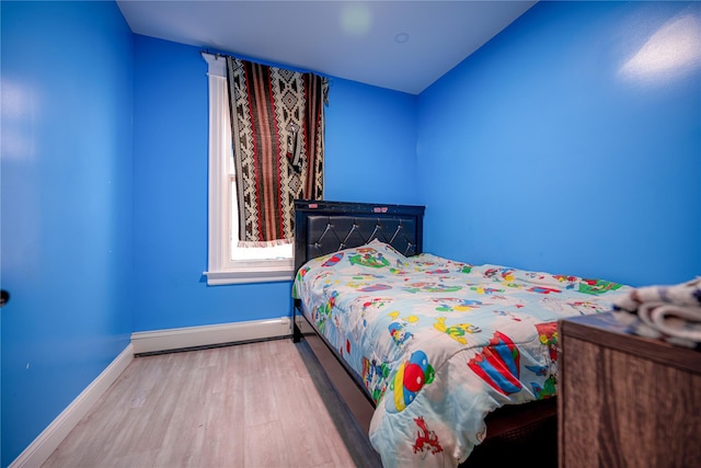 bedroom featuring a baseboard heating unit and light hardwood / wood-style flooring