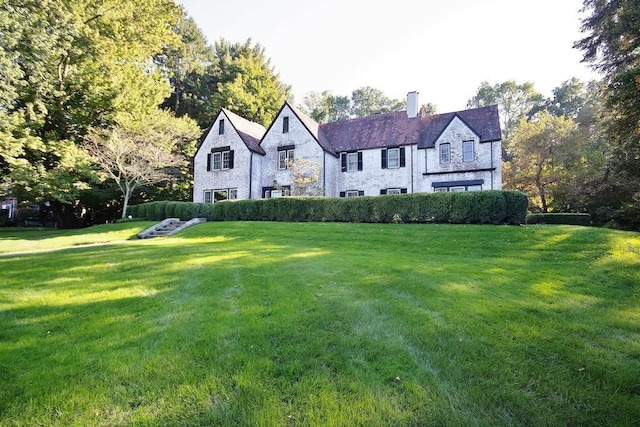 view of front of property with a front yard, stone siding, and a chimney