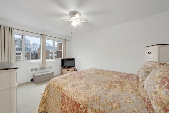 bedroom with radiator heating unit, light colored carpet, and ceiling fan