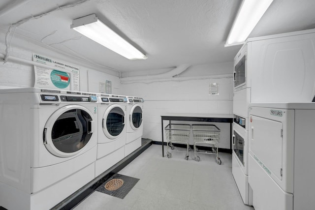 washroom with stacked washing maching and dryer, washing machine and dryer, and a textured ceiling