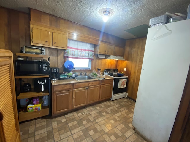 kitchen featuring electric stove, sink, wooden walls, and refrigerator