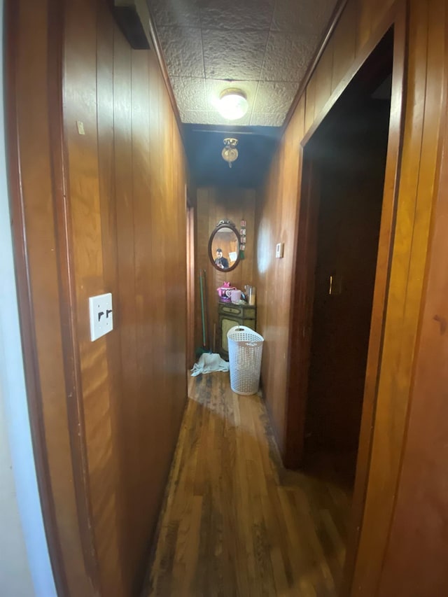 hallway featuring wood-type flooring and wood walls