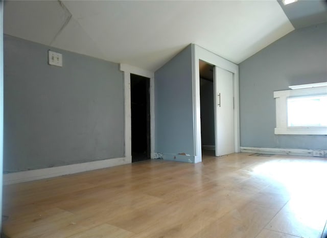 spare room featuring light hardwood / wood-style floors and vaulted ceiling