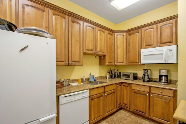 kitchen featuring sink, light stone counters, and white appliances