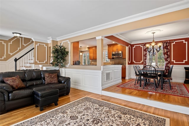 living room with crown molding, a chandelier, and light hardwood / wood-style floors