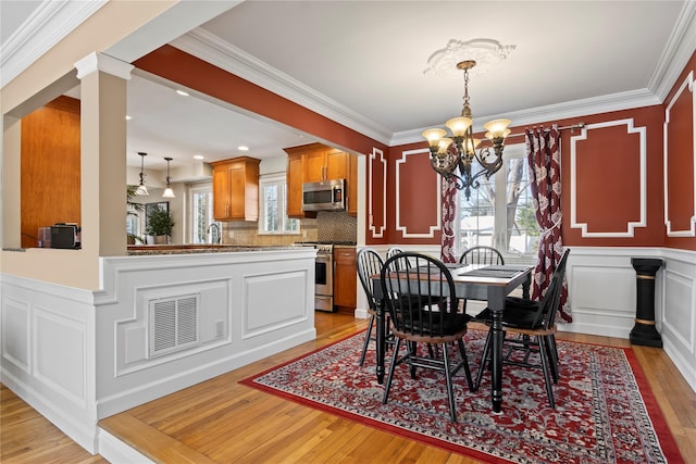 dining space with crown molding, a chandelier, and light hardwood / wood-style flooring