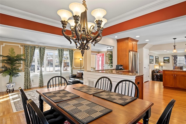 dining space with a notable chandelier, crown molding, and light wood-type flooring