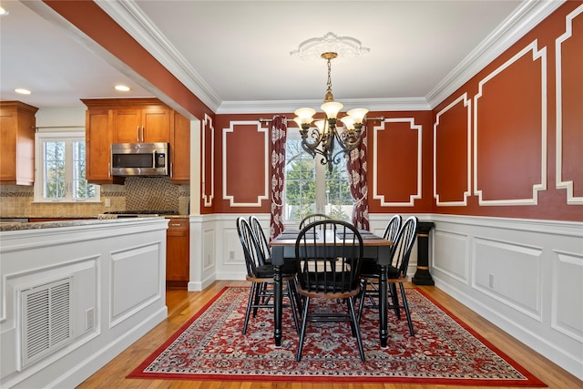 dining room with ornamental molding, light hardwood / wood-style flooring, and a notable chandelier