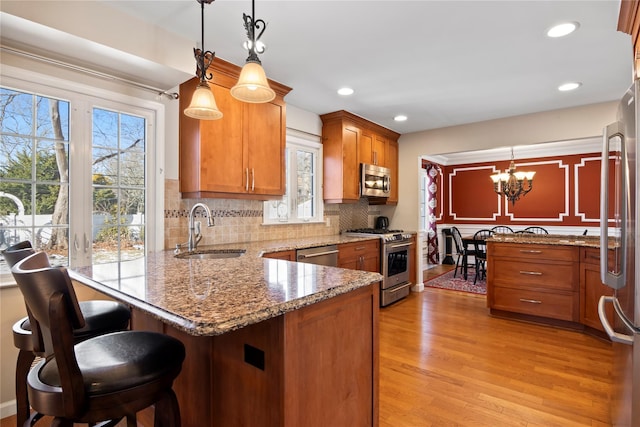 kitchen with sink, decorative light fixtures, a kitchen breakfast bar, kitchen peninsula, and stainless steel appliances