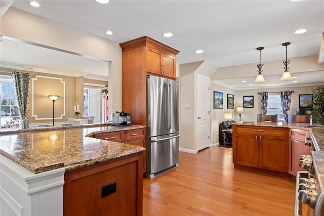 kitchen featuring appliances with stainless steel finishes, plenty of natural light, pendant lighting, and light wood-type flooring