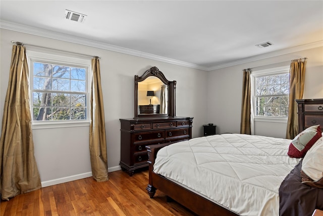 bedroom with multiple windows, hardwood / wood-style floors, and crown molding