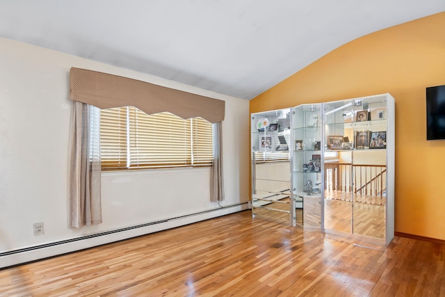 empty room with baseboard heating, lofted ceiling, and hardwood / wood-style floors