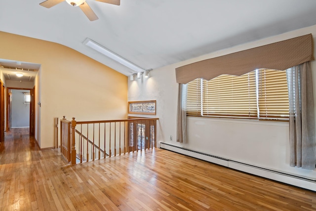 spare room with lofted ceiling, wood-type flooring, ceiling fan, and baseboard heating