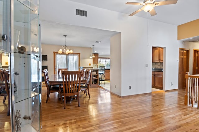 dining space featuring ceiling fan with notable chandelier and light hardwood / wood-style flooring